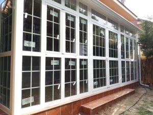 Cerramiento de porche en aluminio blanco con cuarterones sobre murete de ladrillo