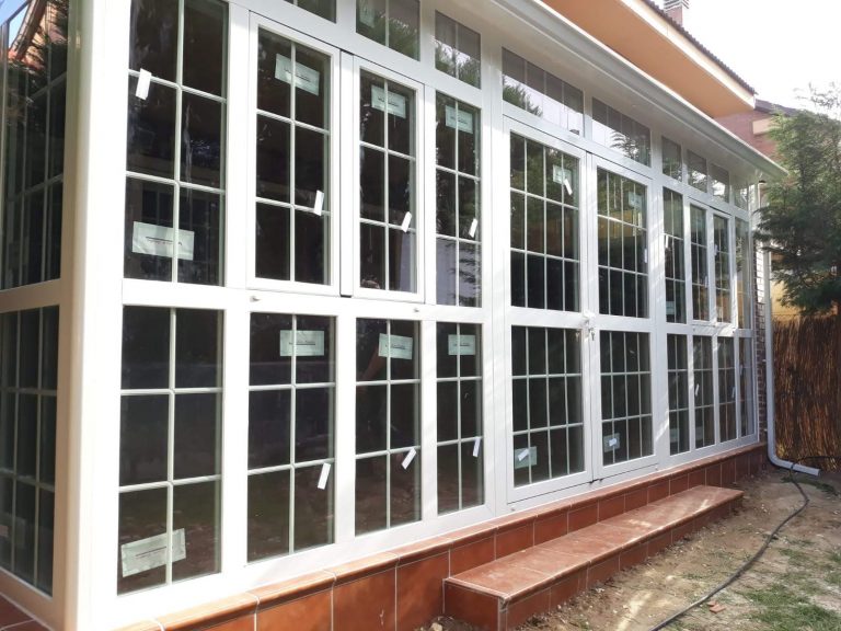 Cerramiento de aluminio blanco con cuarterones sobre murete de ladrillo