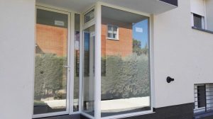 Puerta de entrada y fijos acristalados de aluminio blanco en un edificio