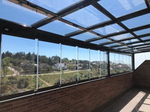Terraza cerrada con perfiles de aluminio, techo de vidrio y vistas al campo