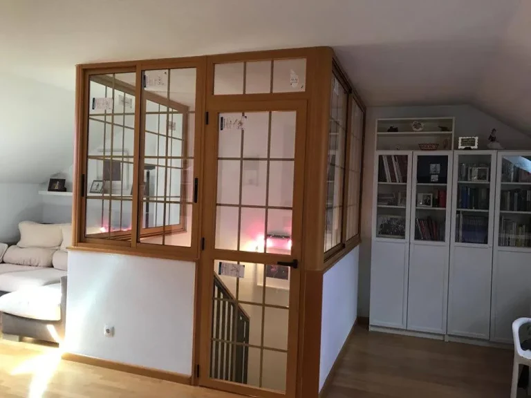 Cerramiento interior de aluminio imitación madera con cuarterones que separa la escalera de un salón abuhardillado