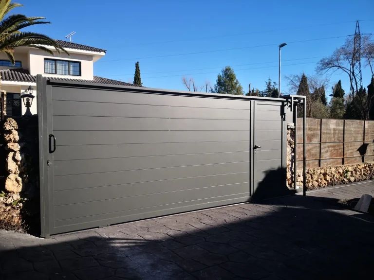 Puerta corredera de vehículos de aluminio gris de lamas horizontales en un chalet