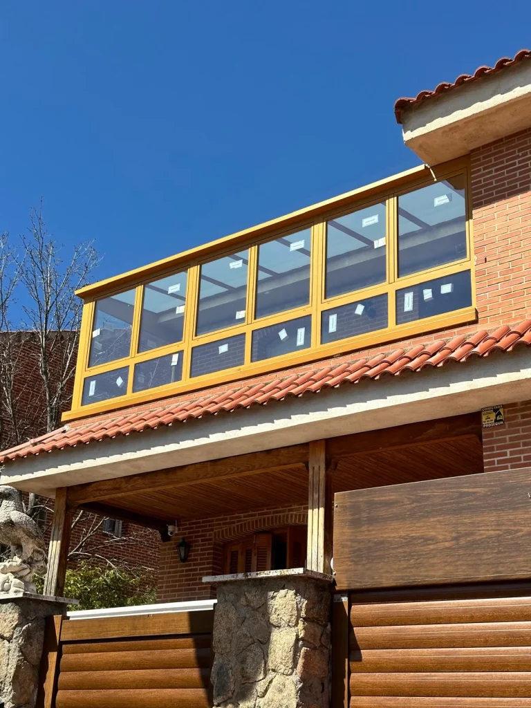 Terraza de la planta alta de un chalet cerrada con aluminio color madera y ventanas correderas